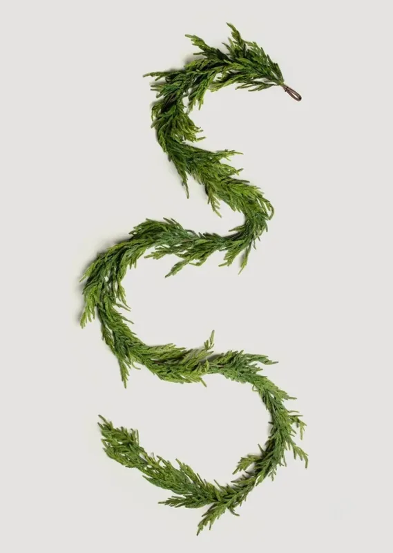 Complete green evergreen garland arranged in an S shape on a neutral background