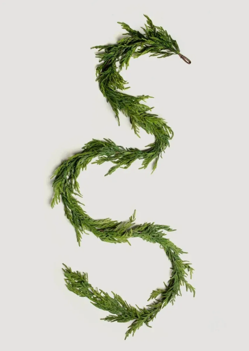 Complete green evergreen garland arranged in an S shape on a neutral background