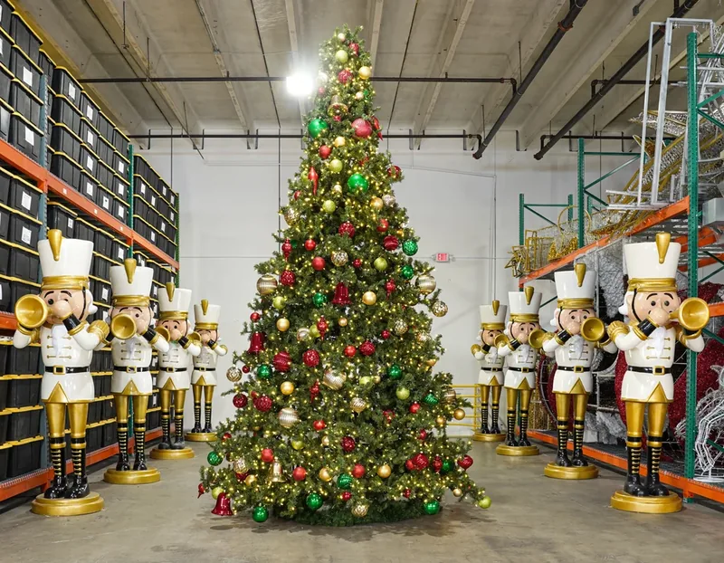 Decorated red green and gold Christmas tree displayed between nutcracker figures