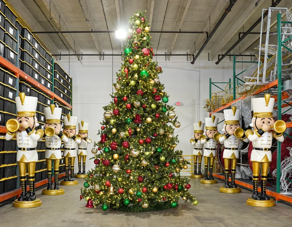 Decorated red green and gold Christmas tree displayed between nutcracker figures