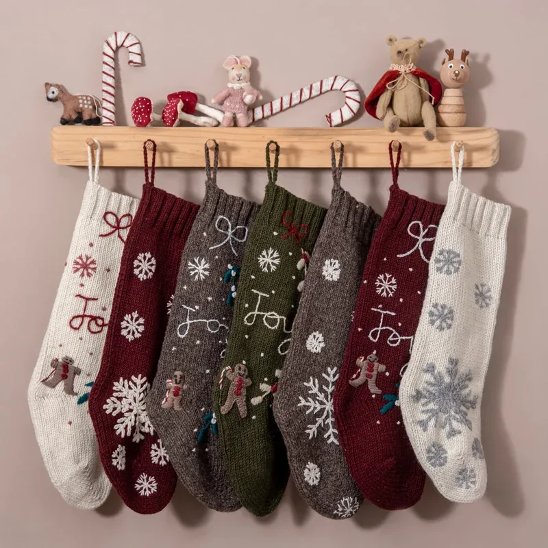 Assorted personalized knit Christmas stockings hanging from a wooden shelf