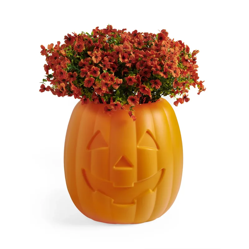 Orange pumpkin-shaped holder filled with flowers on a white background