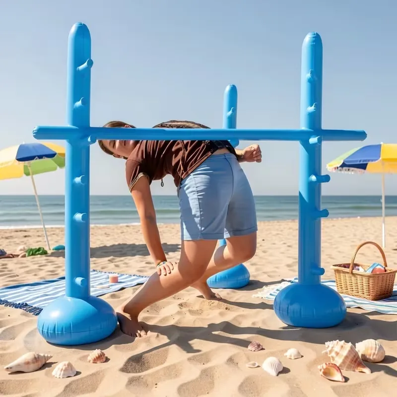 Person playing limbo under a blue freestanding inflatable bar at the beach