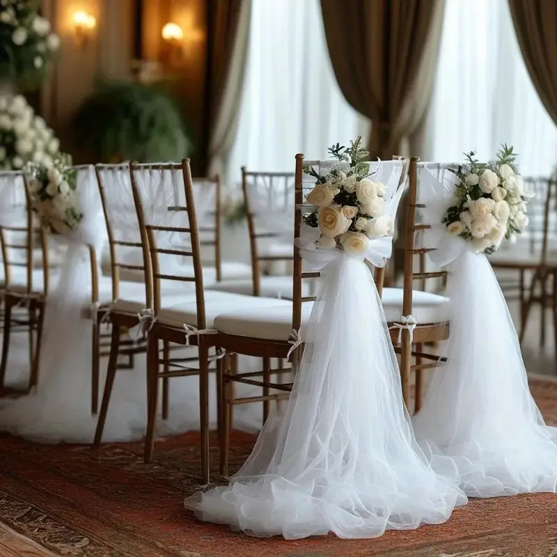 Two wedding chairs decorated with white tulle and floral accents
