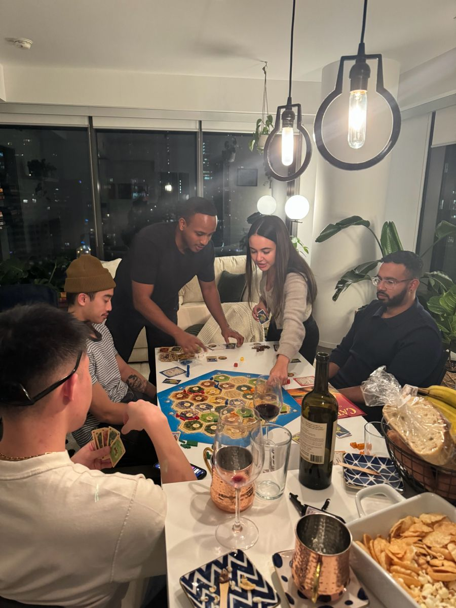 Adults gathered around a dining table playing a board game during a casual game night